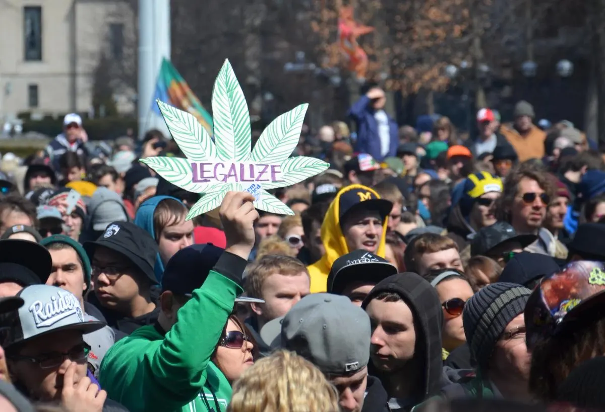 A dense crowd, one person holding up a cannabis leaf sign reading Legalize.