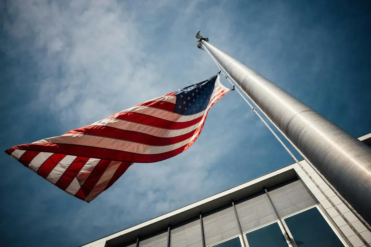 A United States flag flying from a pole outside a civic building.